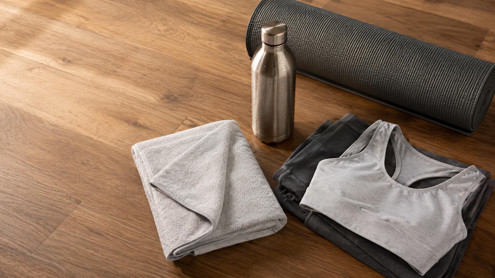 Fitted moisture-wicking yoga clothing, a mat towel and a water bottle laid out before a hot yoga class